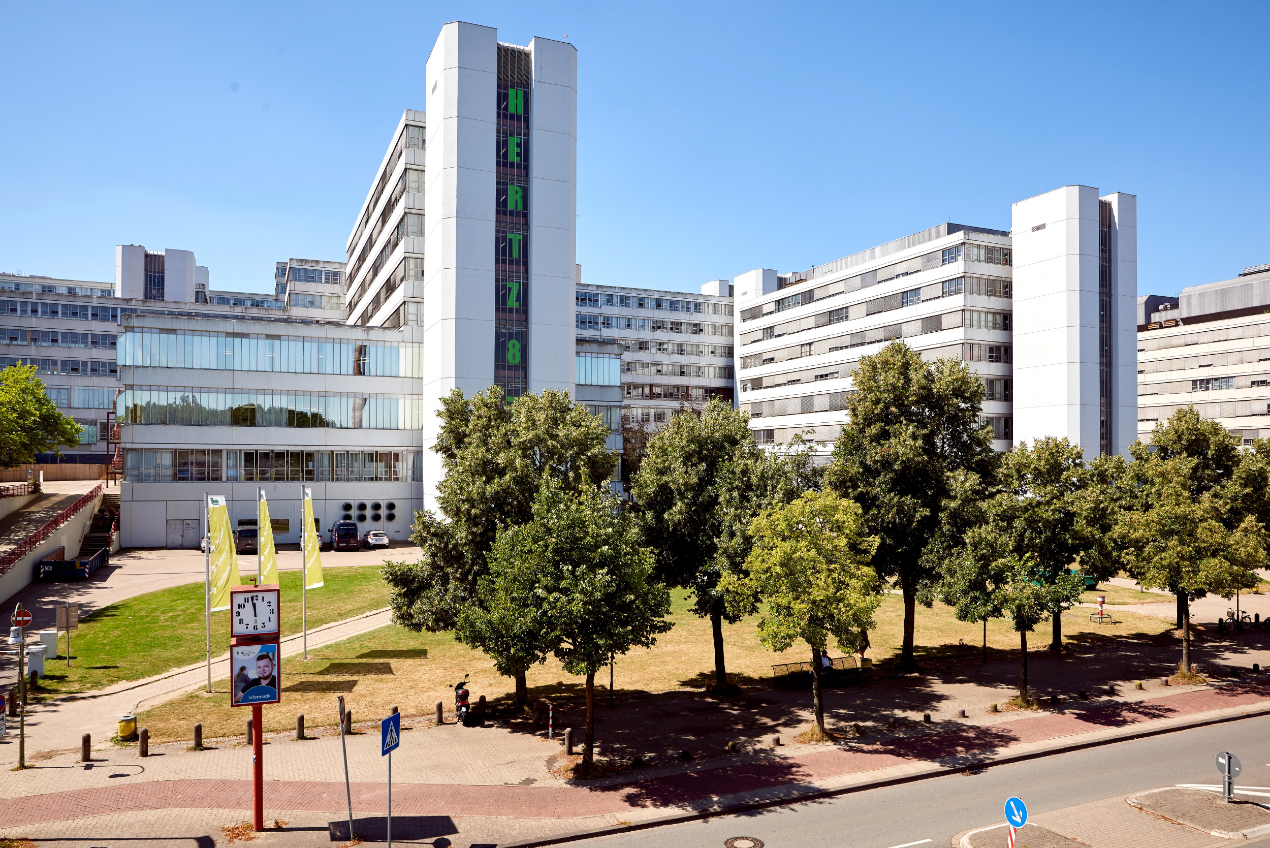 Das Hauptgebäude der Universität Bielefeld hinter Bäumen.